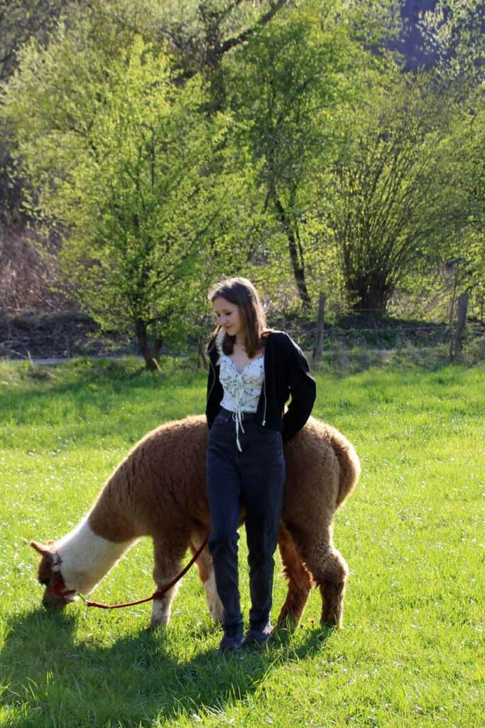 Sarah auf der Wiese mi Alpaka